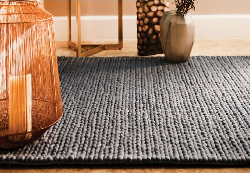 close up of a black braided wool rug