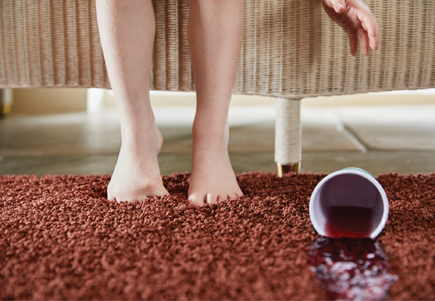 someone dropping a cup of red juice on a red washable rug