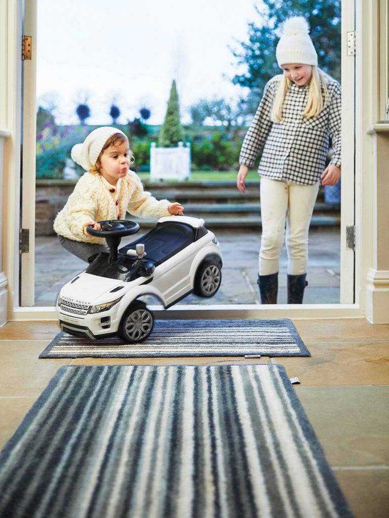 Child is playing with a toy car on a hug rug