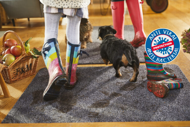 Girl and a dog with dirty feet walking on a hug rug anti viral mat