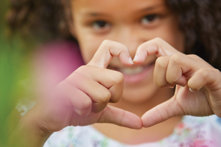 Young girl creating heart shape with her hands